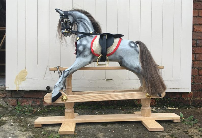 A small antique style dapple grey rocking horse stood outside