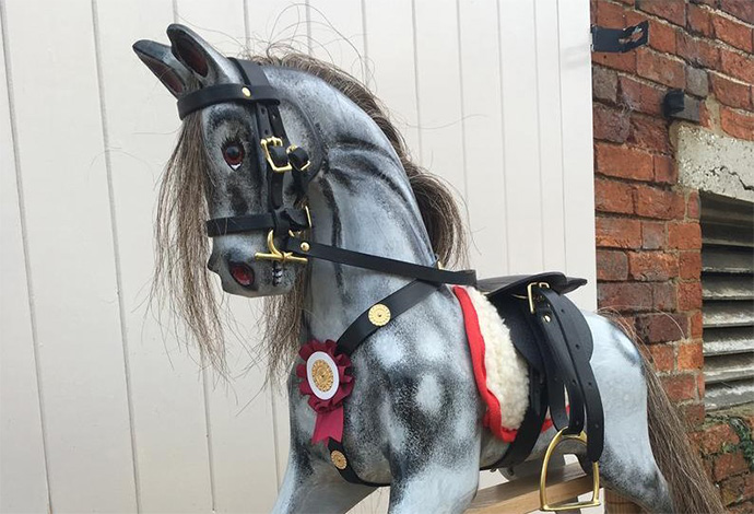 A small antique style dapple grey rocking horse seen diagonally
