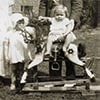 A toddler sitting on a rocking horse surrounded by family