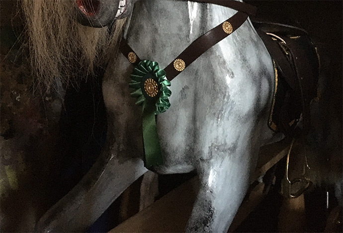 The front torso of a rocking horse wearing a green badge
