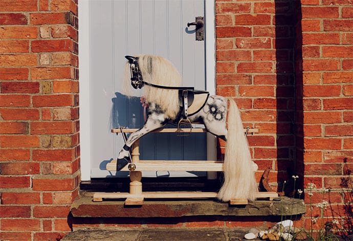 English dapple grey rocking horse next to door outside